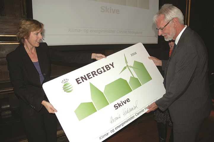 Skive Kommunes tidligere borgmester Flemming Eskildsen (V) modtager energibyskiltet fra Connie Hedegaard. Foto: Skive Kommune. 
